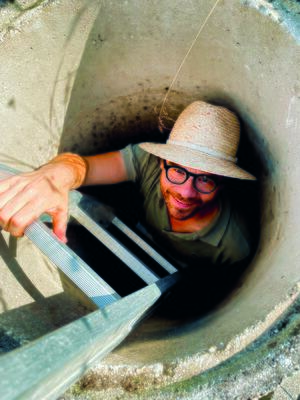 Mann mit Hut steht im Kanalrohr