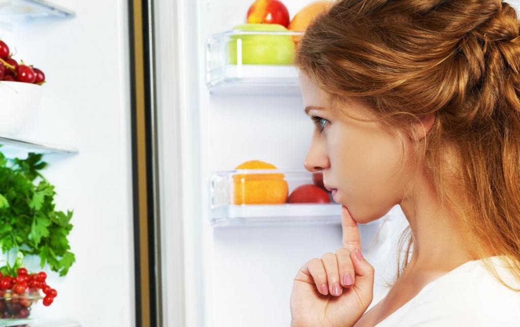 Frau steht vor offenem Kühlschrank (c) 