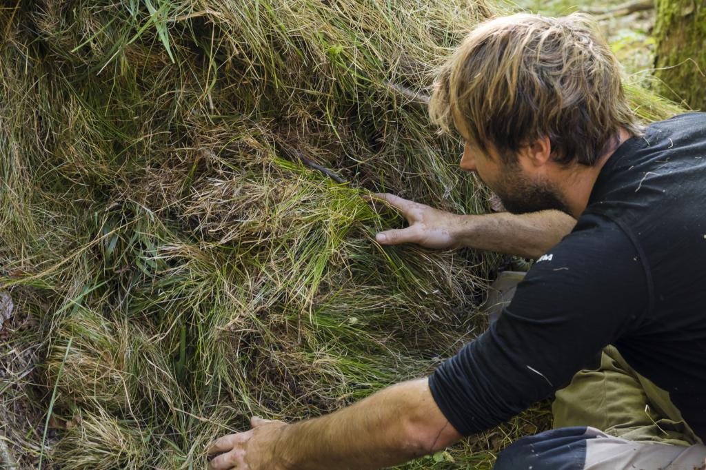 Trümmerhütte: Eingang wird mit Gras abgedichtet © Uwe Grinzinger Trümmerhütte: Eingang wird mit Gras abgedichtet