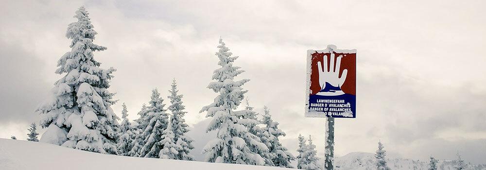 "Lawinengefahr"-Schild in einer Schneelandschaft