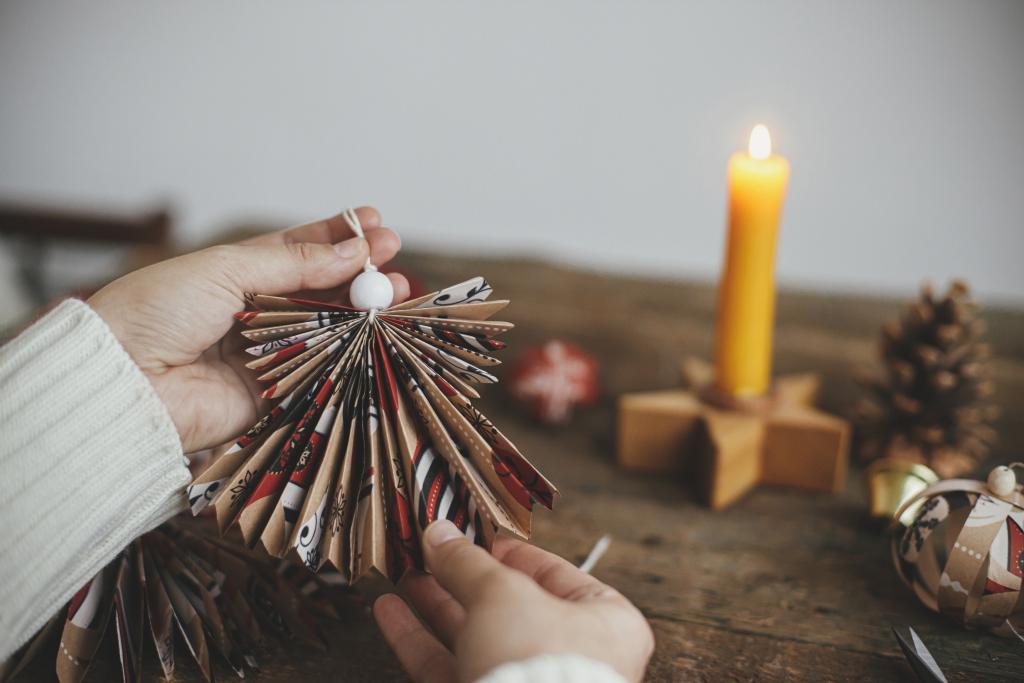 Selbst gebastelter Weihnachtsengel aus Papier, brennende Kerze im Hintergrund