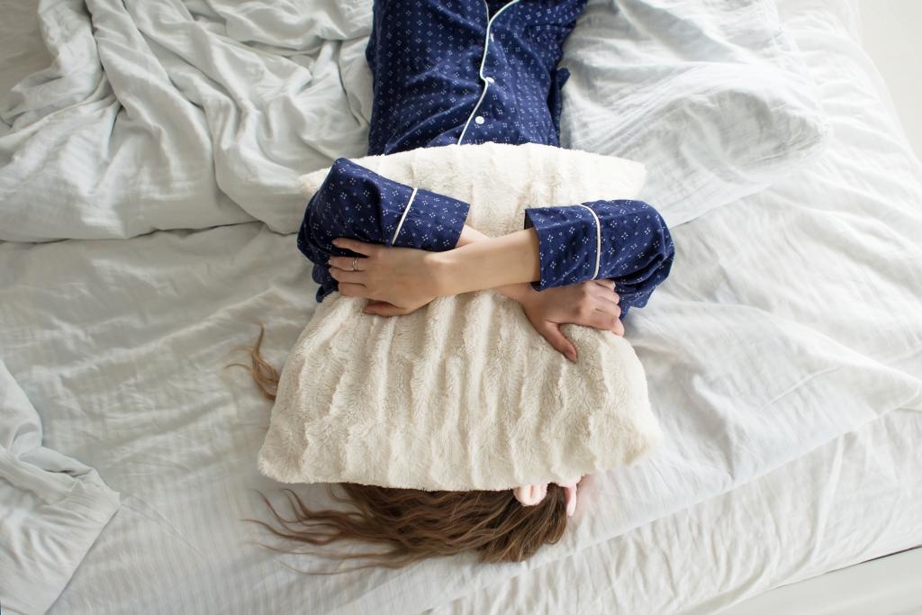 Winterschlaf © lia-koltyrina / www.shutterstock.com Frau hält sich Polster im Bett über den Kopf