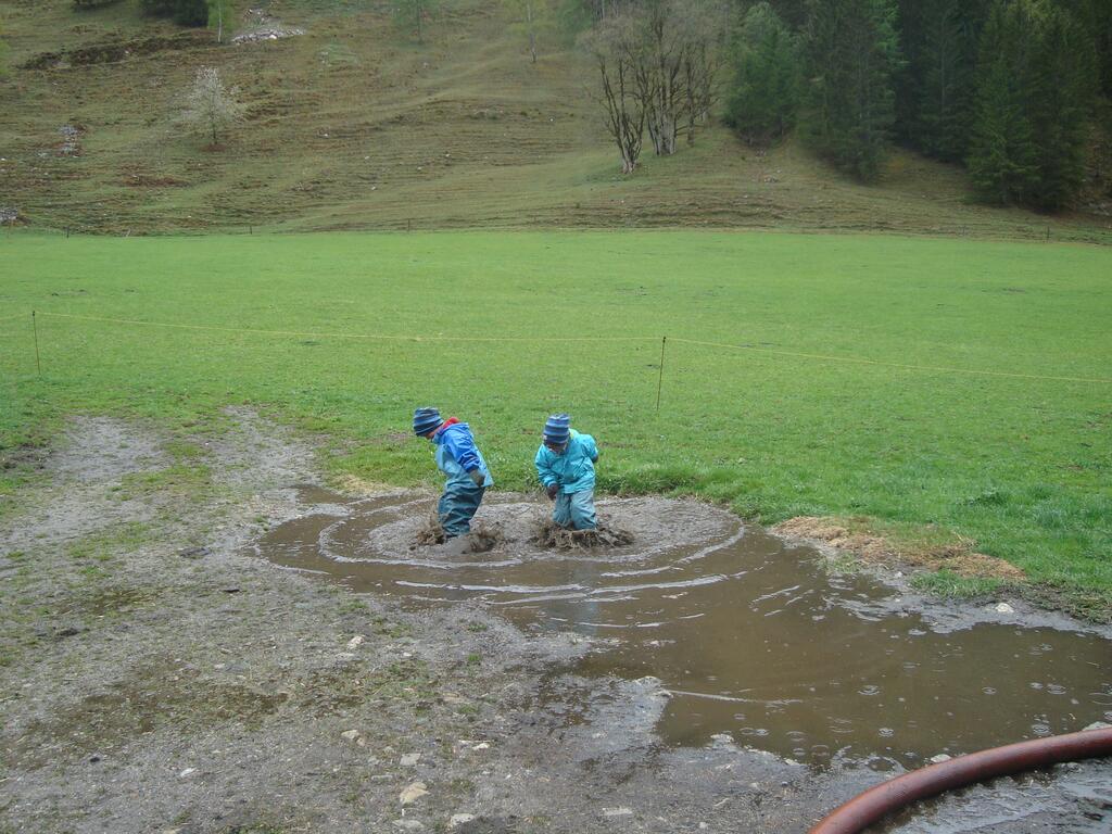 Kinder hüpfen in einer Gatschlacke