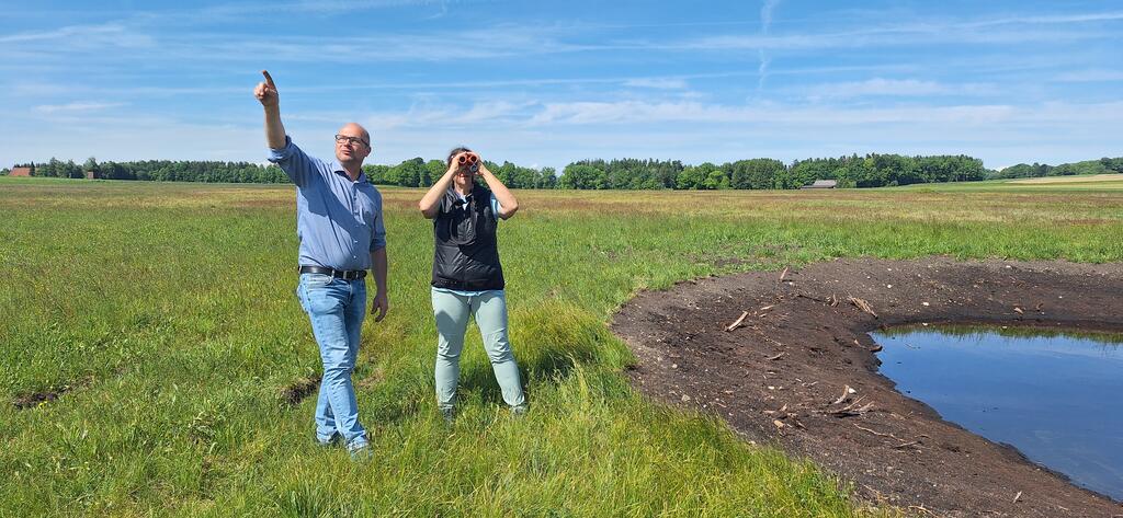 Landwirt Christian Danter schafft mit Landschaftsplanerin Claudia Arming sechs Feuchtlebensräume inmitten von extensiven Wiesen. © Wolfgang Suske Zwei Menschen stehen mit Fernglas in einem sumpfigen Gebiet
