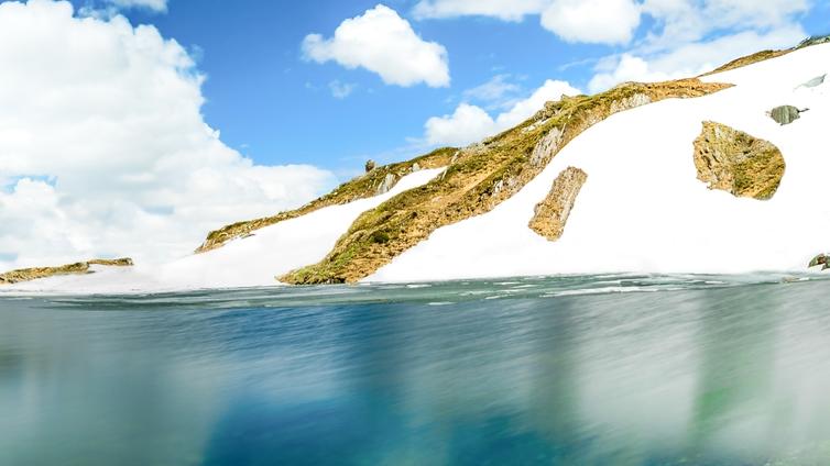 Schneefelder bedecken die Ufer des Bergsees