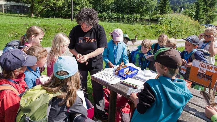 Die Naturvermittlerin zeigt den Kindern der Schulklasse verschiedene Fundstücke.