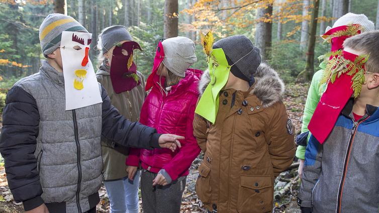 Kinder mit Masken im Wald.