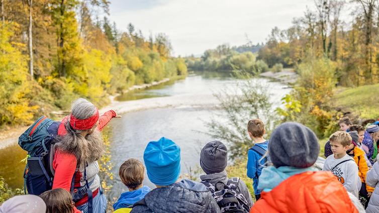 Die Naturvermittlerin, Martha Riess, zeigt den Kindern einer Schulklasse die Unterhimmler Au.