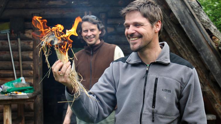 Die Kunst des Feuermachens © Steigenberger Zwei Männer entzünden Feuer in einem mit Gras befüllten Stück Birkenrinde