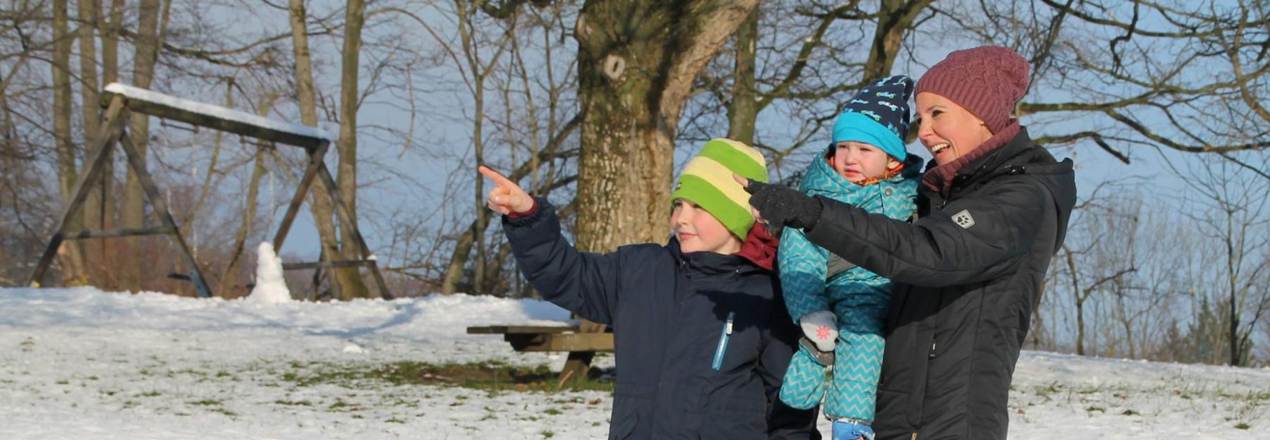 Familie im Schnee zeigen auf etwas