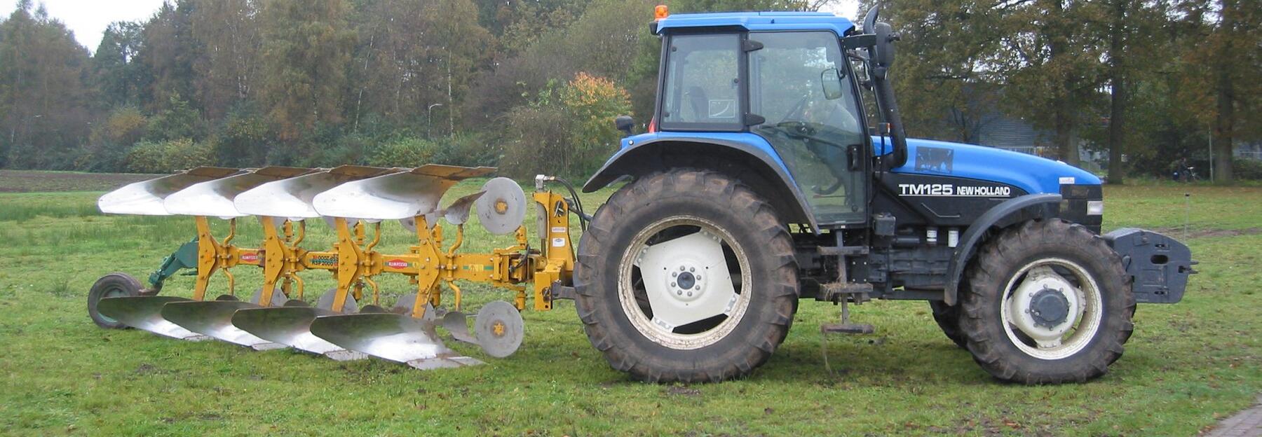 Blauer Tracktor mit einem Pflug