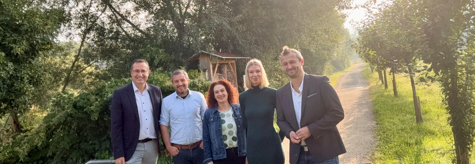 Eine Gruppe von fünf Menschen auf einem Weg zwischen Hecken