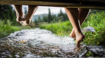 Kinder spielen in der Natur, auf einer Brücke über einem Bach