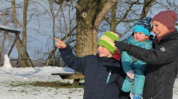 Familie im Schnee zeigen auf etwas