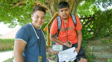 Zwei junge Burschen sind mit ihren GPS-Geräten auf der Suche nach dem Schatz im Buchenwald.