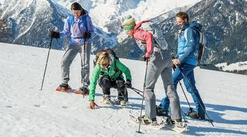 Vier Personen mit Schneeschuhen in eindrucksvoller Winterlandschaft.