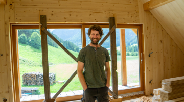 Gregor Rinesch steht in seinem Dachboden aus Holz