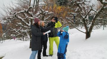 Personen mit Feldstecher beim Vogelbeobachten im verschneiten Garten