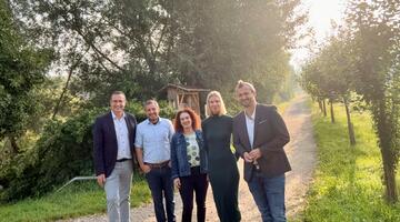 Eine Gruppe von fünf Menschen auf einem Weg zwischen Hecken