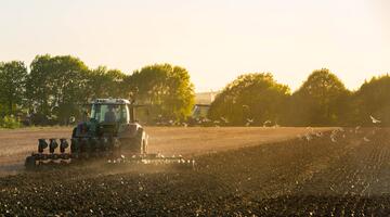 Traktor beim Pflügen im Sonnenaufgang