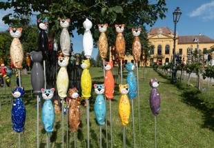 Gartendeko in Form von bunten Katzen vor der barocken Westfassade von Schloss Eckartsau