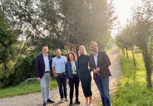 Eine Gruppe von fünf Menschen auf einem Weg zwischen Hecken